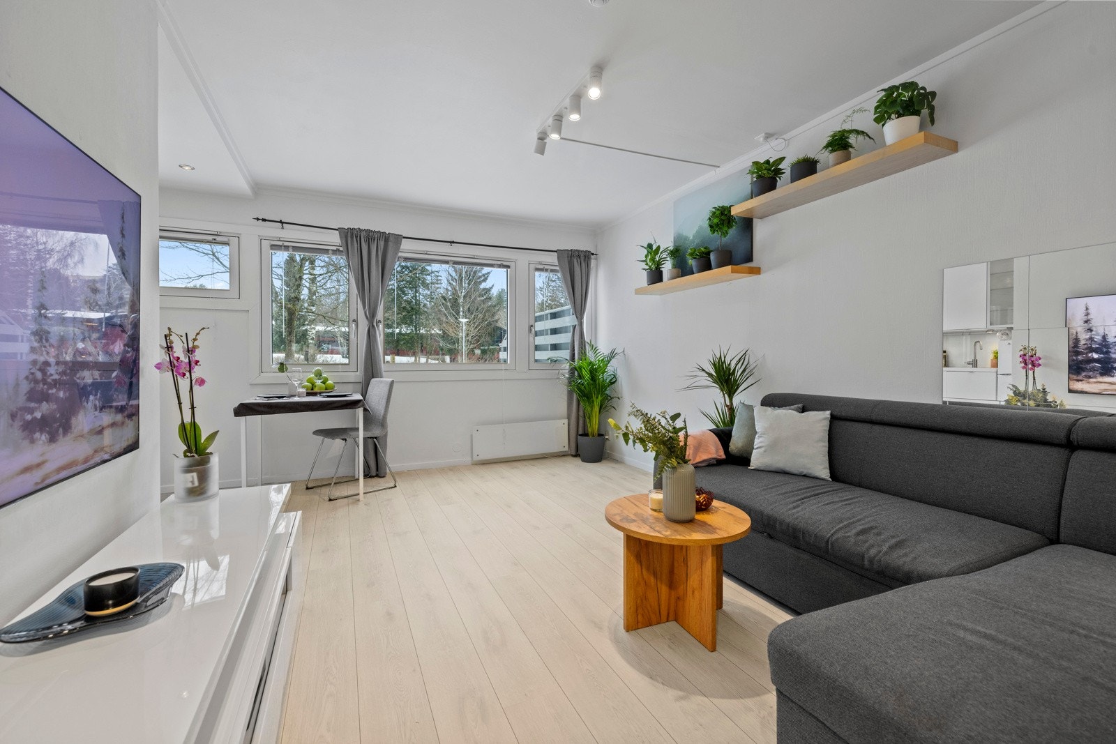 Innenfor entreen danner stuen og kjøkkenet et åpent allrom, med godt lysinnslipp via en rekke vinduer i front Galleribilde