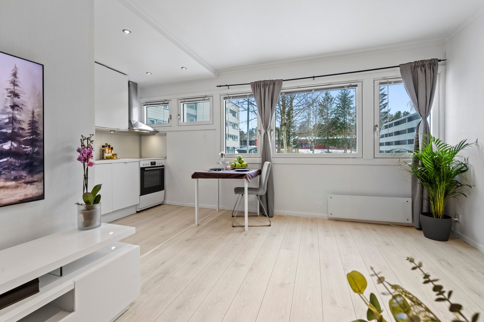 Vinduene bringer inn noe av det grønne, og stuen har 1-stavs laminatgulv og lysegrå veggflater Galleribilde