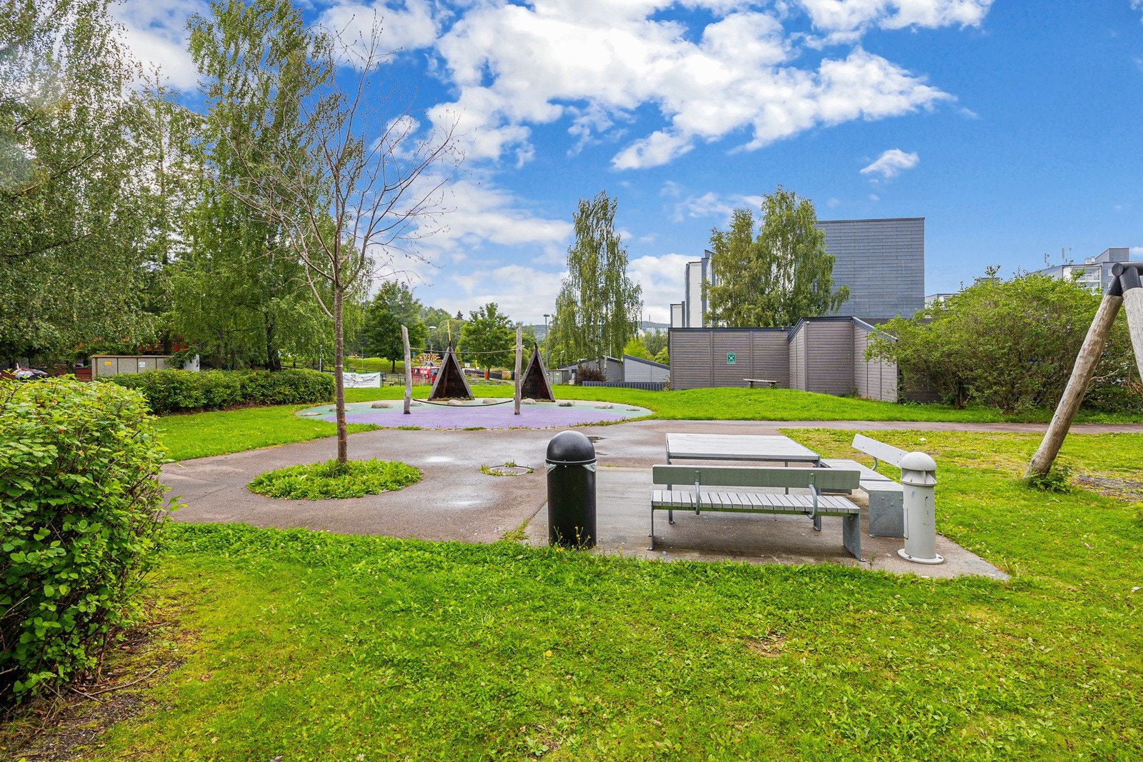 Rundt blokka har borettslaget et pent fellesområde med sittegrupper, store grøntarealer, asfalterte internveier og flere lekeplasser Galleribilde