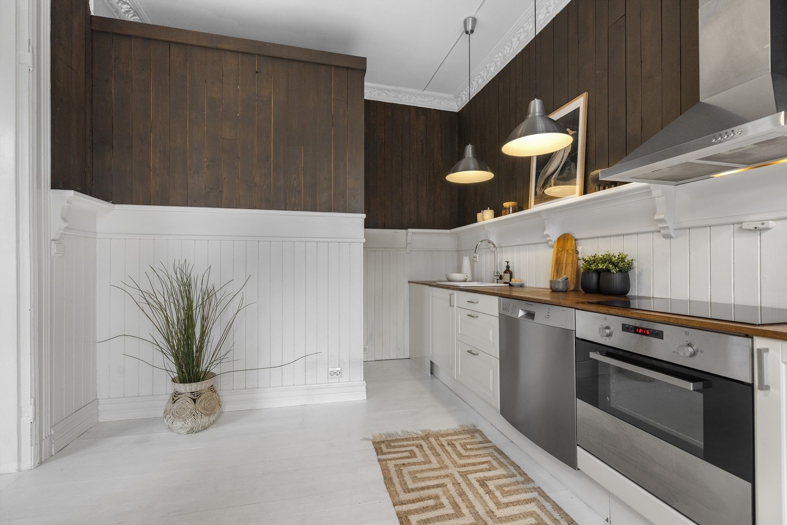 Kjøkkeninnredningen har profilerte hvite fronter, heltre benkeplate med nedfelt keramisk kum med ettgreps blandebatteri. Videre er kjøkkenet utstyrt med integrerte hvitevarer, inkludert induksjonstopp, stekeovn og halvintegrert oppvaskmaskin Galleribilde