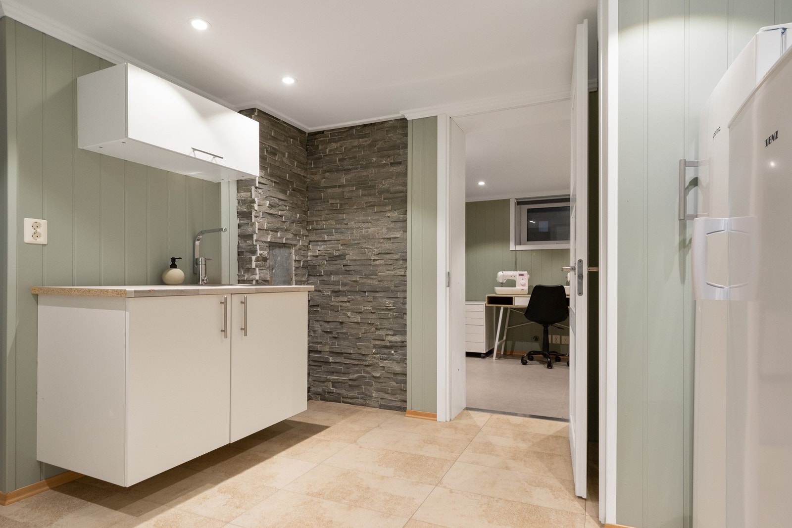 En vinklet kjellerstue er et perfekt rom for ungdommen i familien, og har til og med et eget, enkelt grovkjøkken i egen sone. Galleribilde