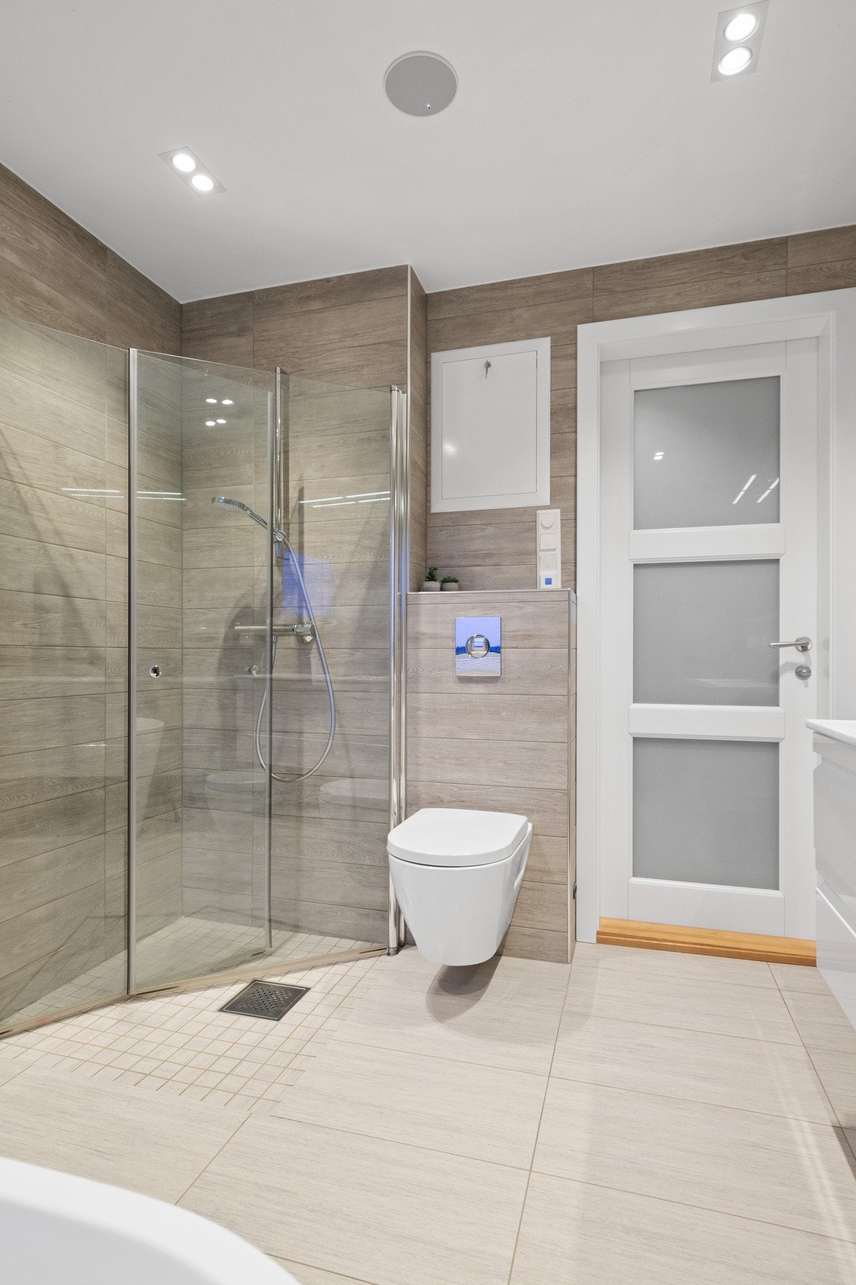 Rommet innbyr til velvære og egentid med delikate fargevalg og et moderne badekar, og det er montert stemningsfulle downlights i himlingen. Galleribilde