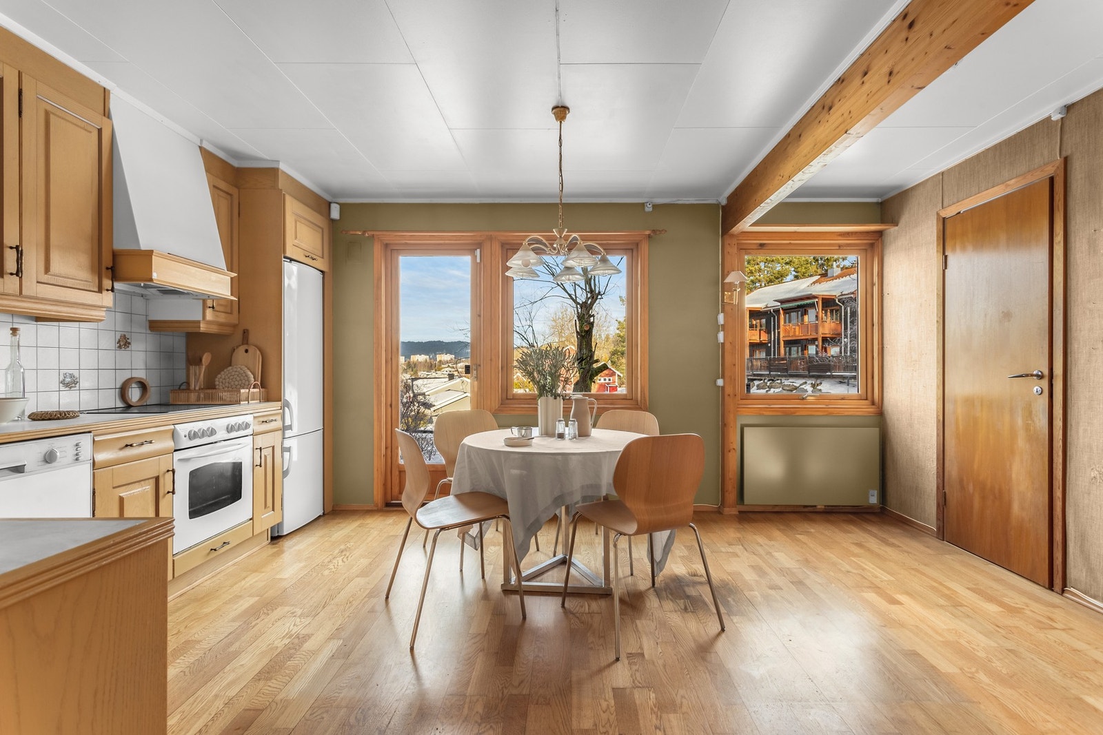Lyst kjøkken med treinnredning og spiseplass ved vinduet. Galleribilde