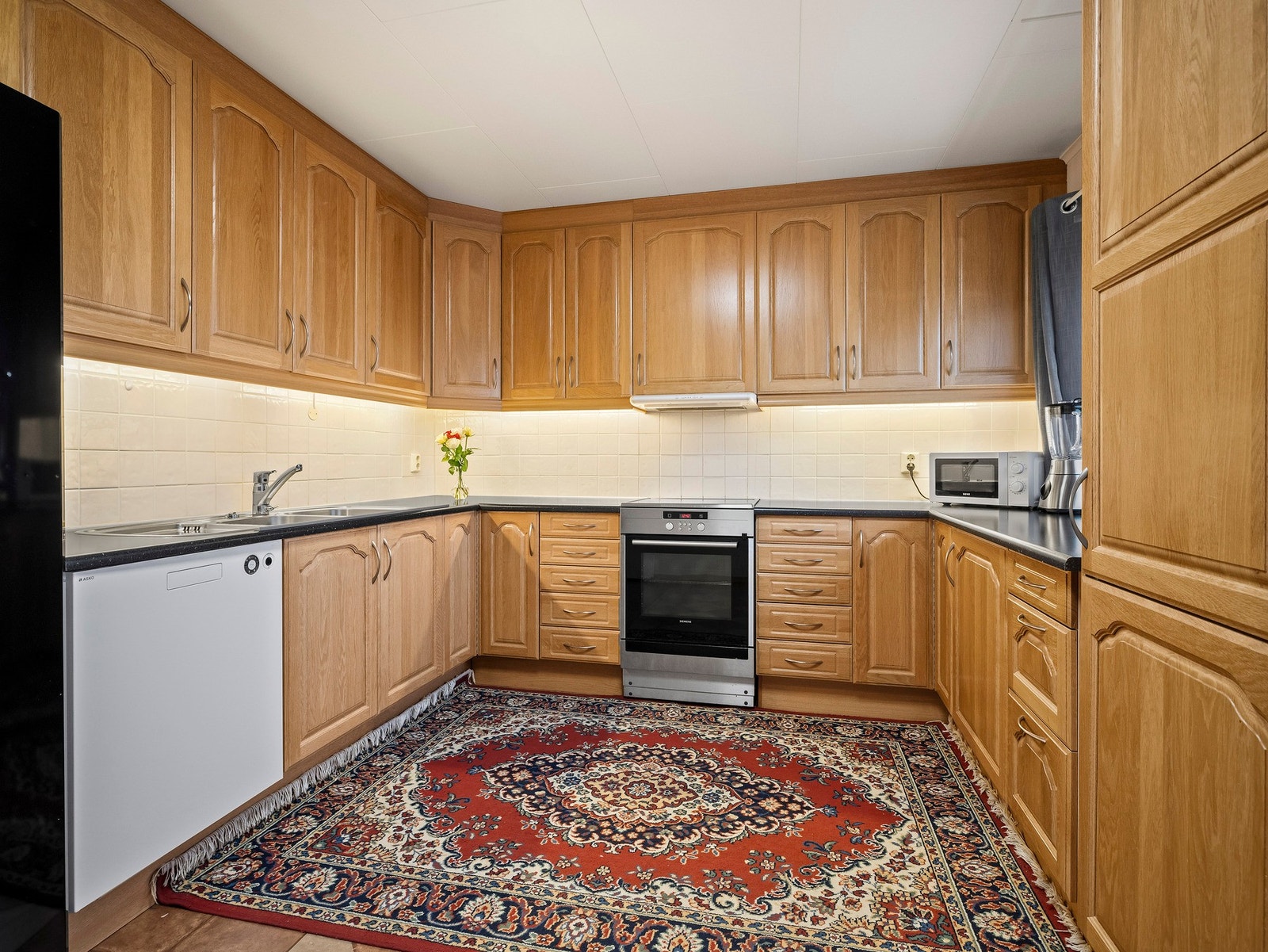 Sigdal kjøkkeninnredning fra 2004 med profilerte fronter i eik og laminat benkeplater. Galleribilde