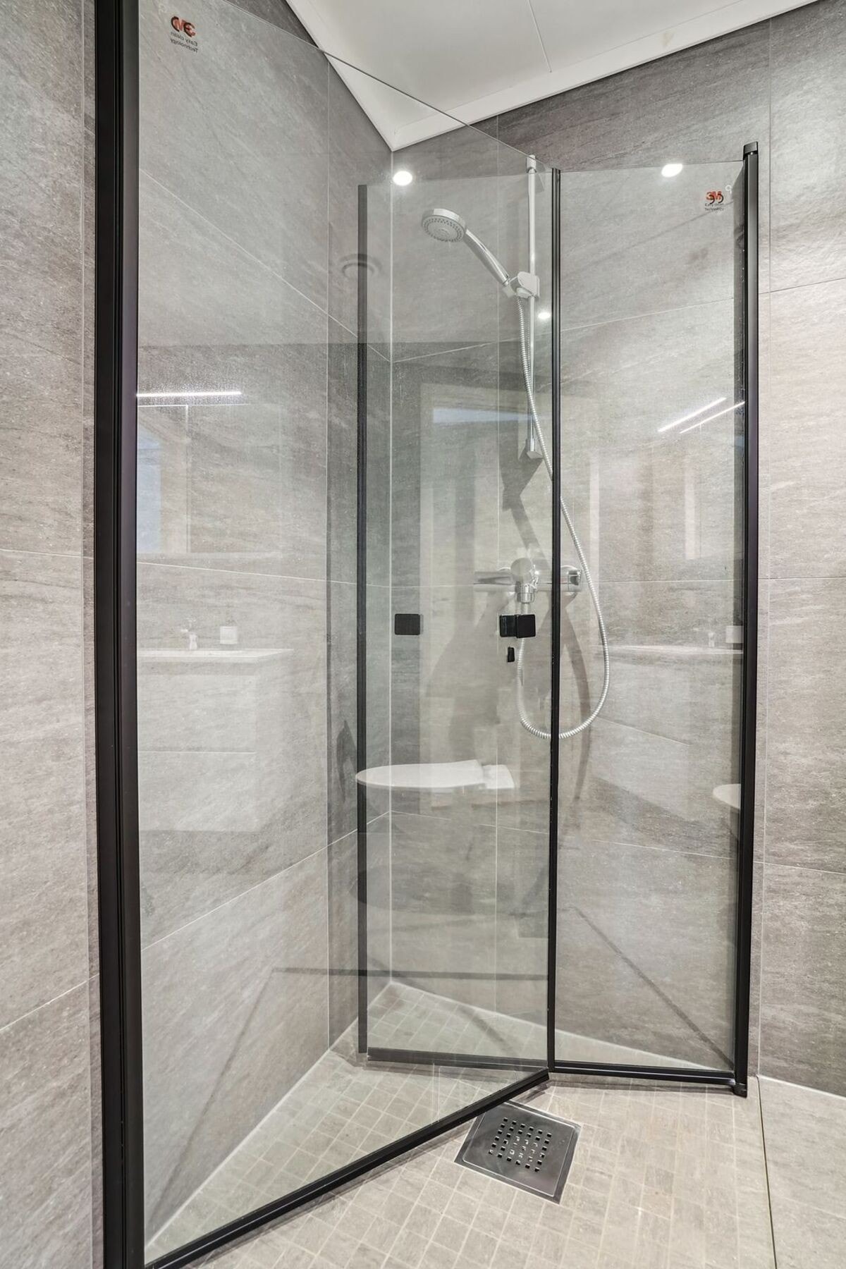 Badet er utstyrt med bla. dusjhjørne med innsvingbare glassdører med sorte detaljer. Galleribilde