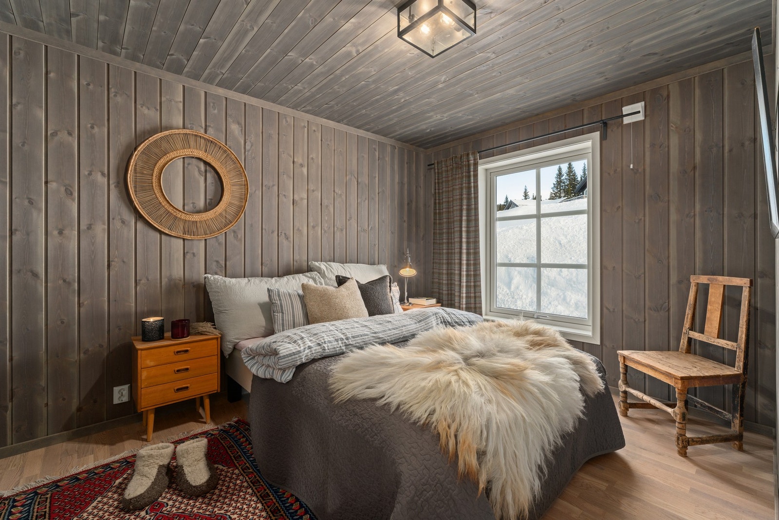 Soverommet har panelvegger og -tak i en gråbeiset finish. Store vinduer slipper inn naturlig lys og gir utsikt til snødekte omgivelser. Gulvet er i lys parkett. Galleribilde