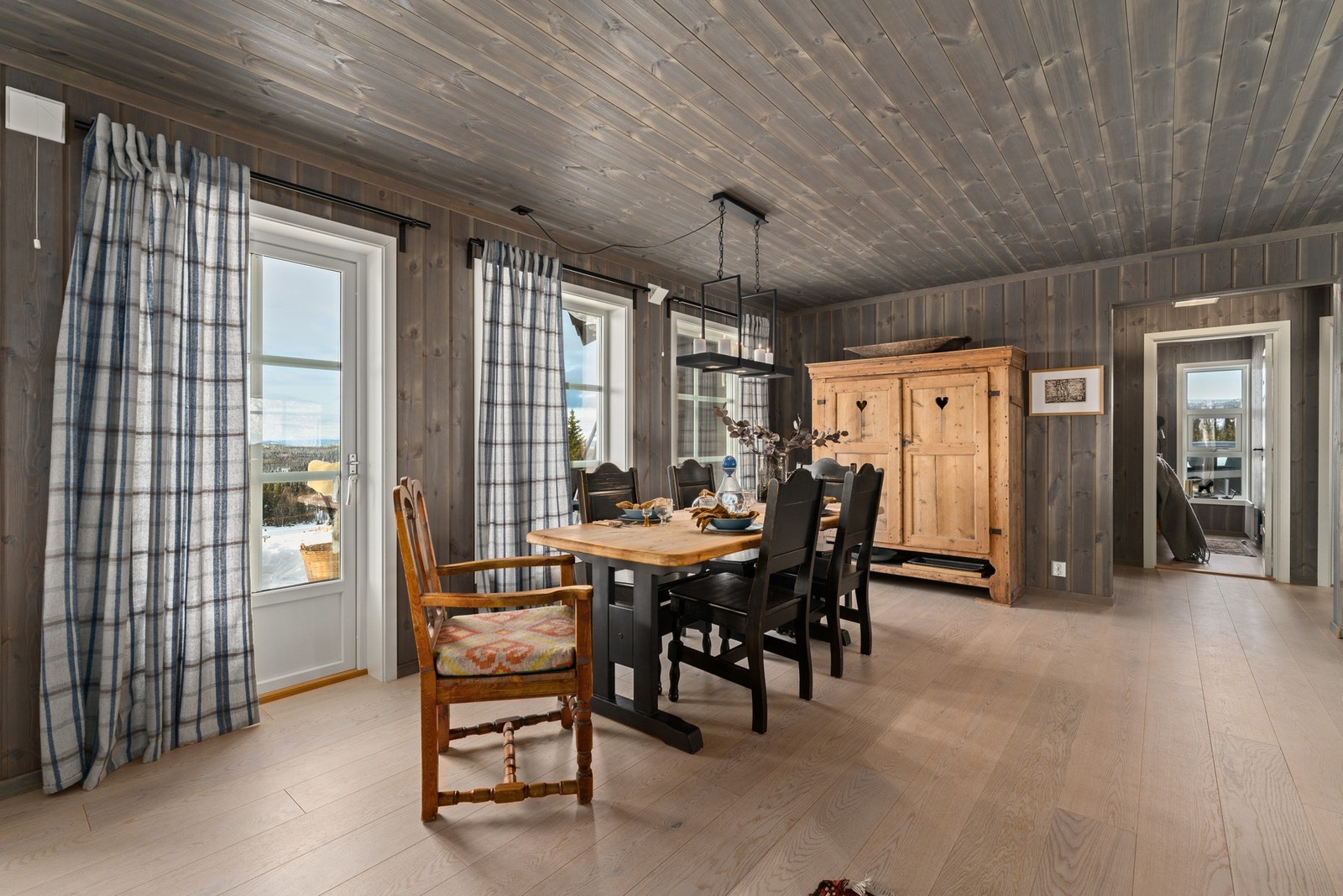 Spiseplassen har trepanel på vegger og tak, store vinduer med utsikt, samt en solid spisestue med plass til flere personer. Rommet er lyst og innbydende med naturlig lysinnslipp. Galleribilde