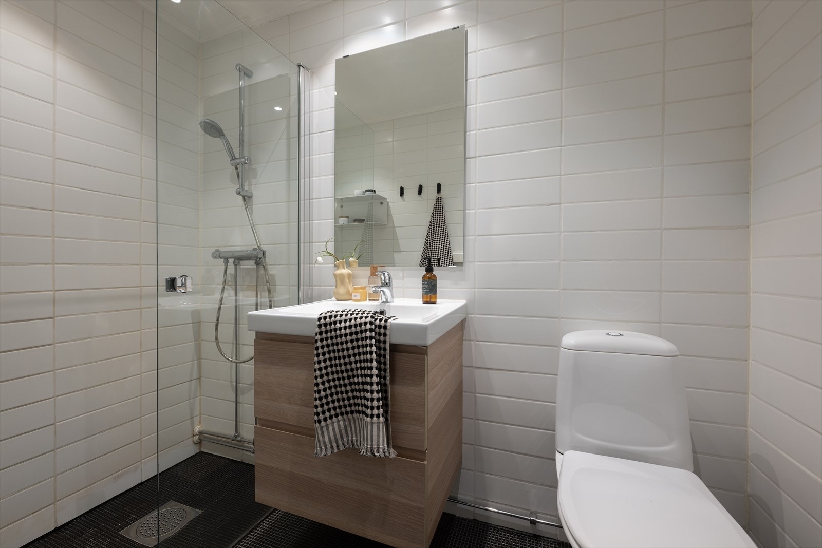 Flislagt baderom med varmekabler i gulv og downlights i himling - Badet er utstyrt med dusj med innfellbar dør i herdet glass og gulvmontert toalett Galleribilde