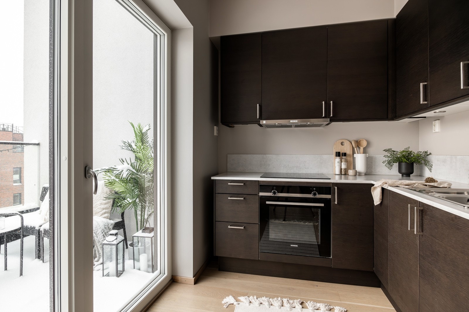 Stilrent og moderne kjøkken fra Sigdal med mørke slette fronter og benkeplate i kompakt laminat med nedfelt kum i rustfritt stål med tilknyttet ett-greps armatur. Galleribilde