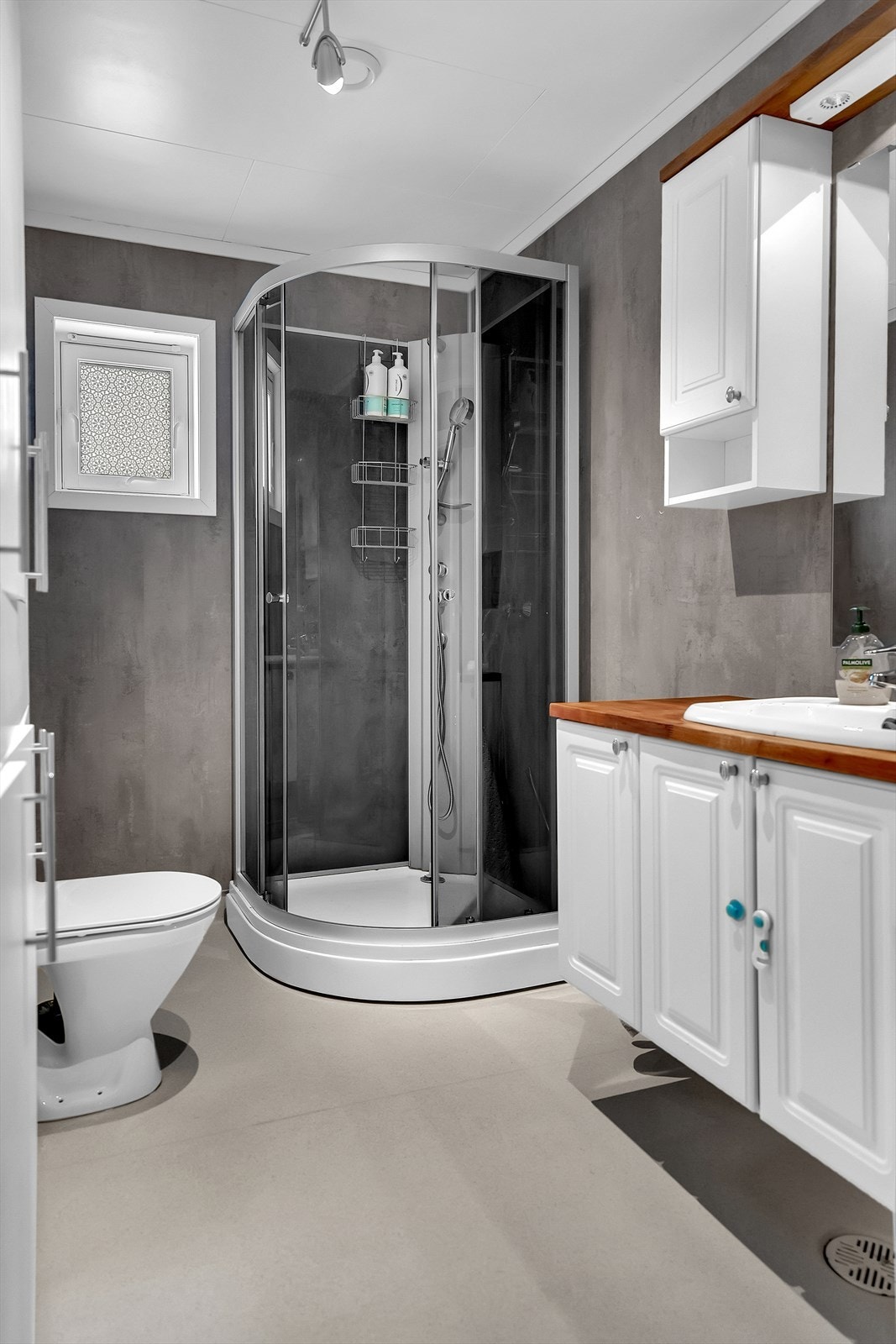 Innredning med hvite profilerte fronter, benkeplate i tre og høyskap for ekstra lagring. Galleribilde