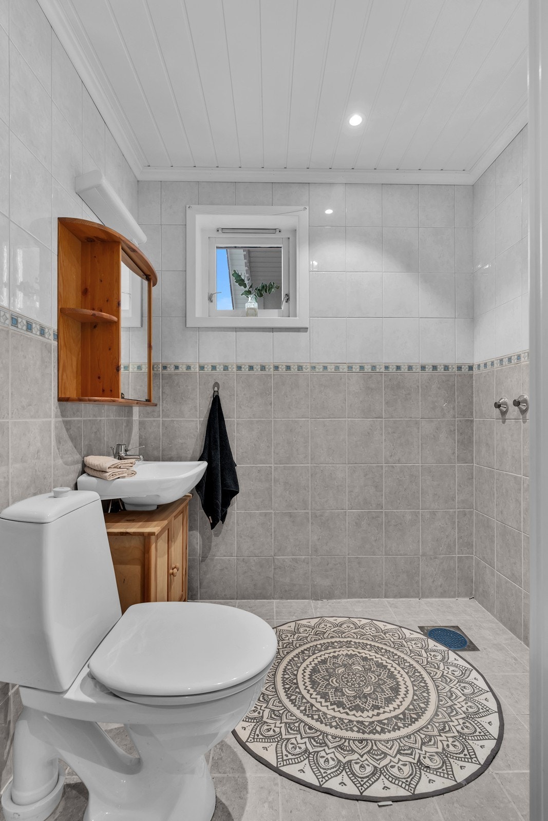 Bad i 1.etasje. Overflater av fliser med elektriske varmekabler i gulv. Nedfelt servant og opplegg for dusj. Galleribilde