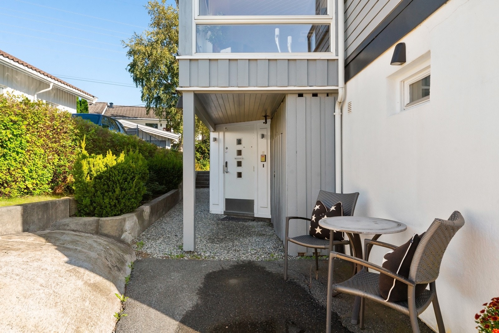 På vestsiden ligger inngangspartiet med overbygg og kodelås på ytterdøren, og på baksiden er det egen inngang til en innredet praktikantdel i underetasjen. Galleribilde