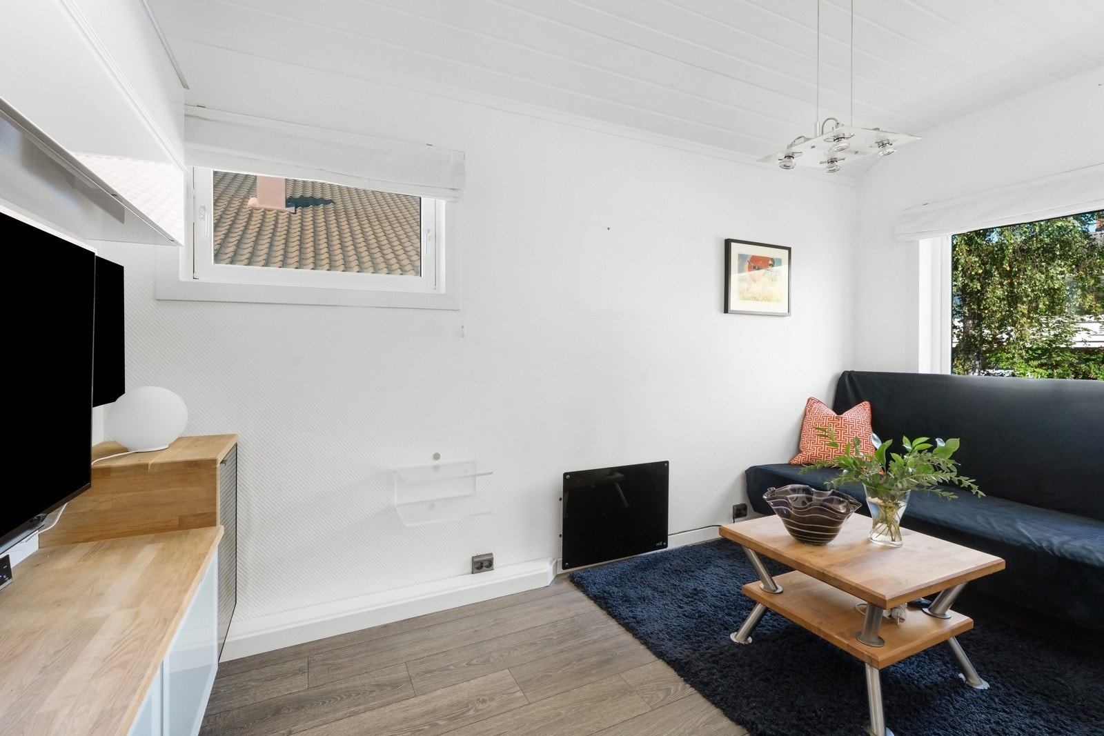 Soverommet i første etasje er lysmalt og innredet med veggmontert tv-seksjon, benkeplate i tre, veggskap over TV-plassen. Galleribilde