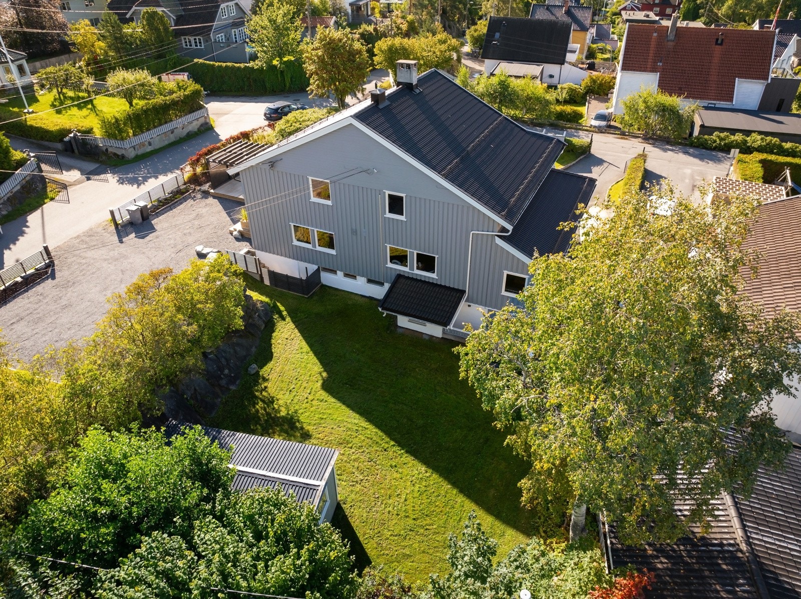 Utearealer omkranses av en tettvokst hekk og har dobbel smijernsport med belysning mot veien. Galleribilde