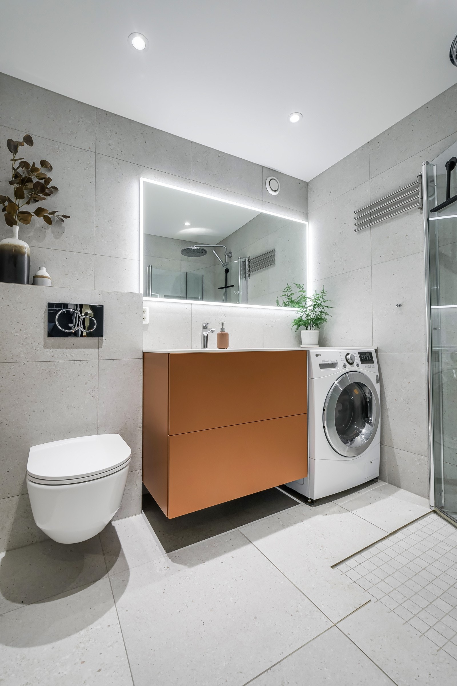 Stilig med mørk baderomsinnredning, spesialbestilt fra Italia med skuffer og ovenpåliggende servant med ett-greps armatur. Stort veggspeil med sidebelysning. Galleribilde