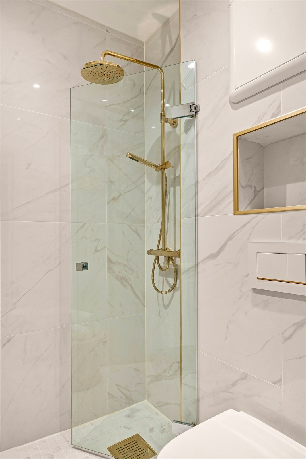 Stilige detaljer i gullfarge, mot delikate fliser i marmorstil. Galleribilde