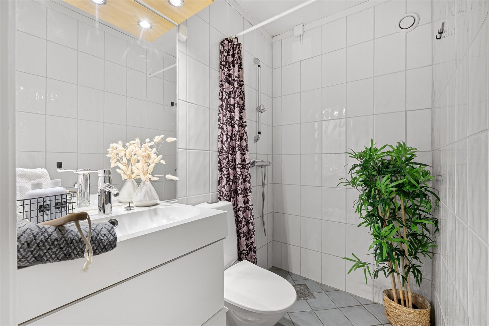 Badet er delikat flislagt med hvite tidløse fliser på veggene i kombinasjon med grå gulvfliser. Galleribilde