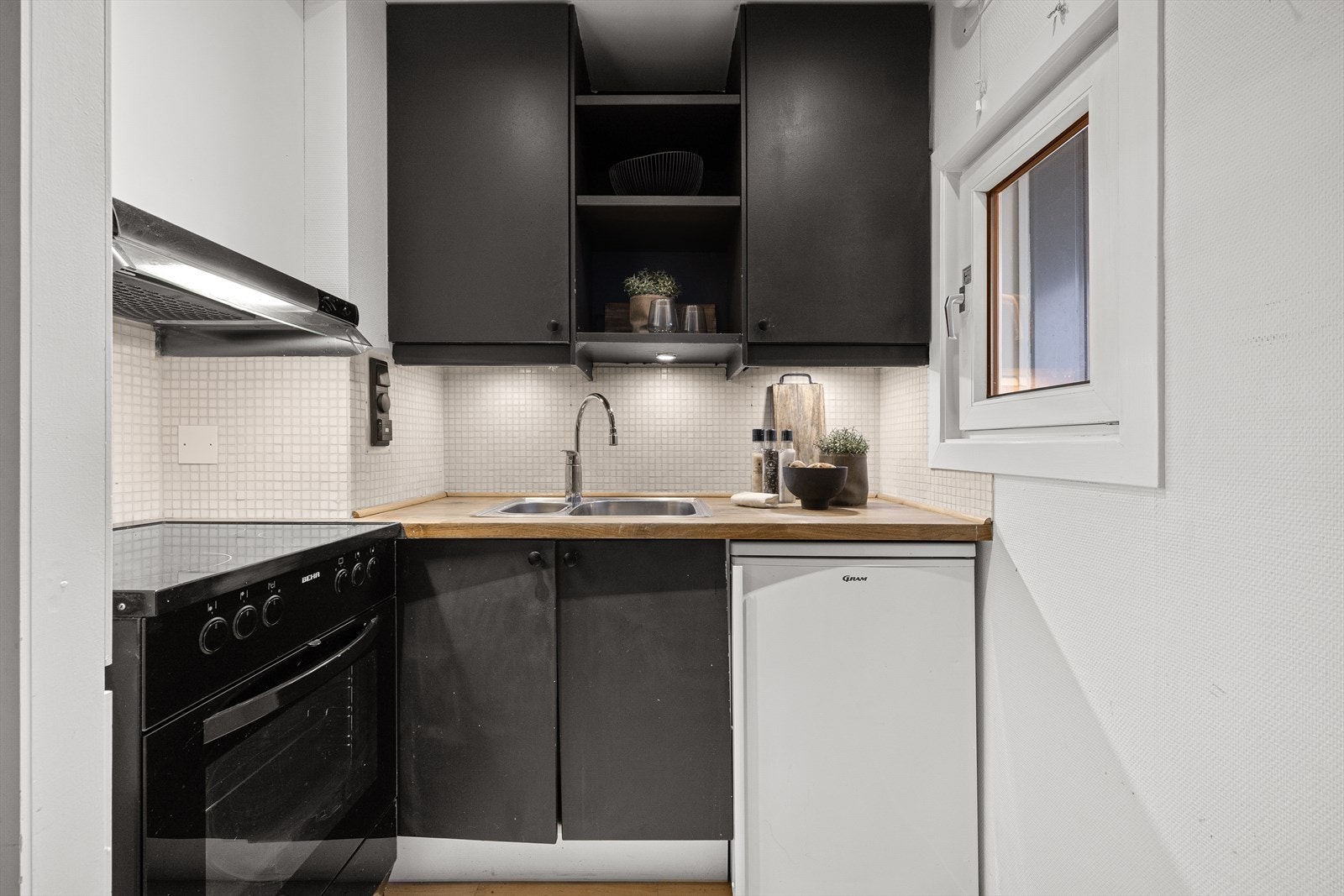 Kjøkkenet har frittstående komfyr og kjøleskap, samt fliser som backsplash - en både praktisk og estetisk detalj. Galleribilde