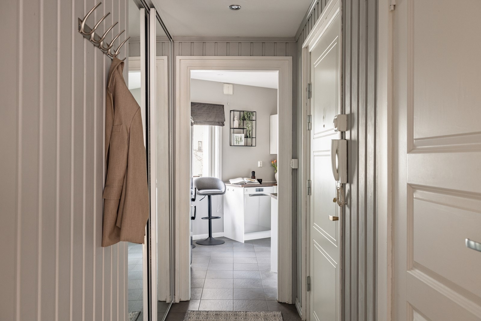 Velkommen inn i en lys entré med flislagt gulv og gulvvarme for ekstra komfort. Malt panel på veggene gir et klassisk uttrykk. Galleribilde