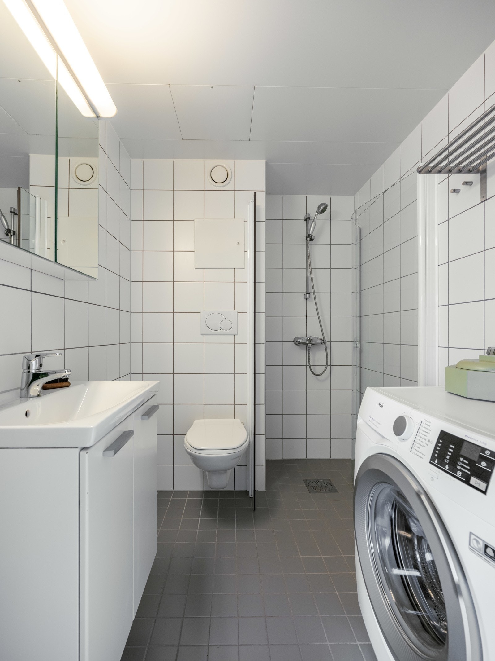 Pent, flislagt bad fra 2005 innredet med vegghengt toalett, servant med underskap, speilskap og dusjhjørne med glassdører. Galleribilde