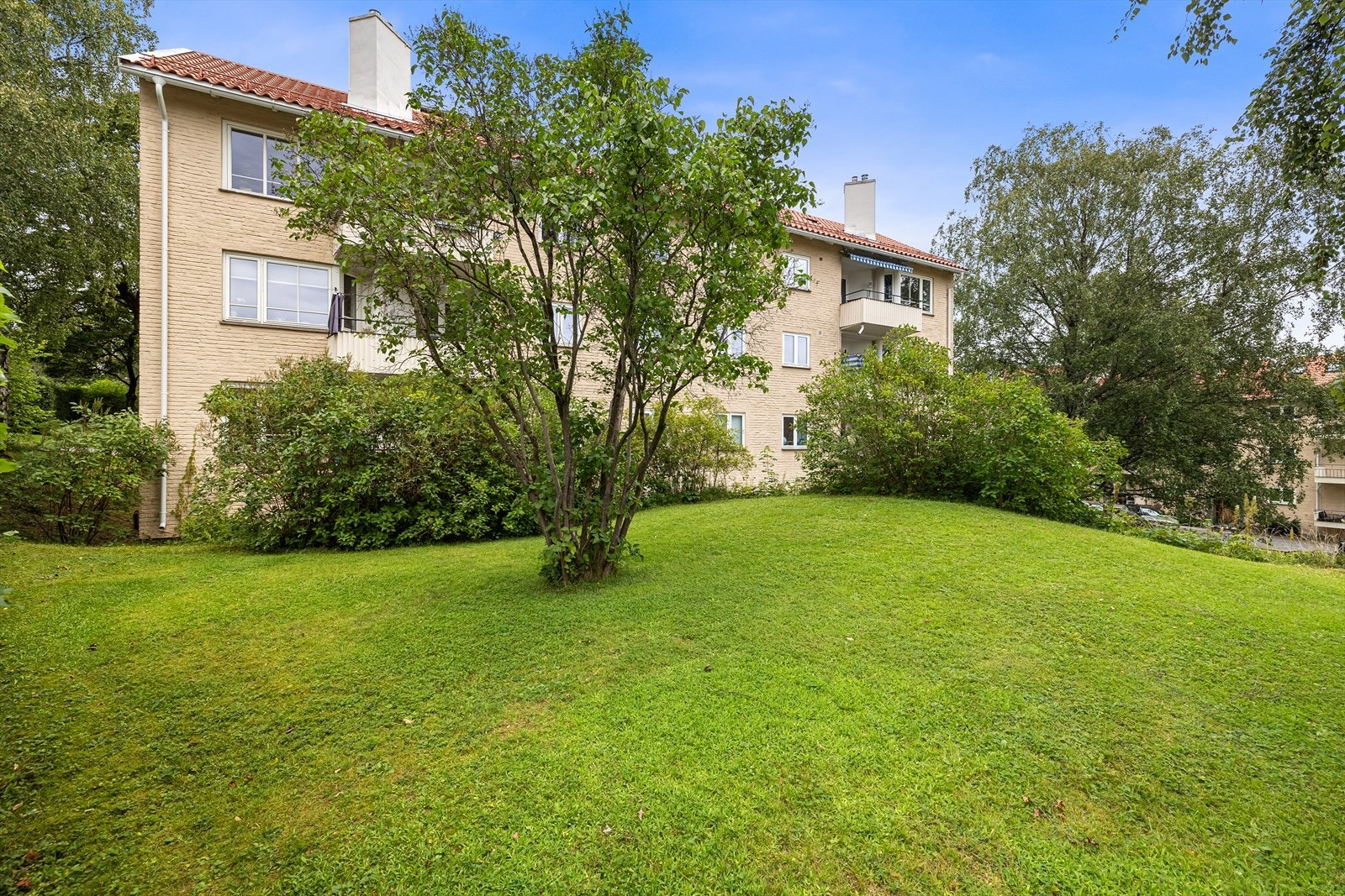 Fra sameiet på sommerstid. Leiligheten har en fin endebeliggenhet i byggets 1. etasje Galleribilde