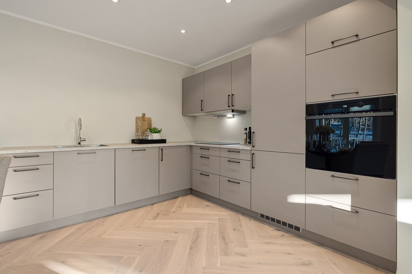 Nytt og moderne HTH kjøkken med slette fronter, sorte stålhåndtak og foliert benkeplate Galleribilde