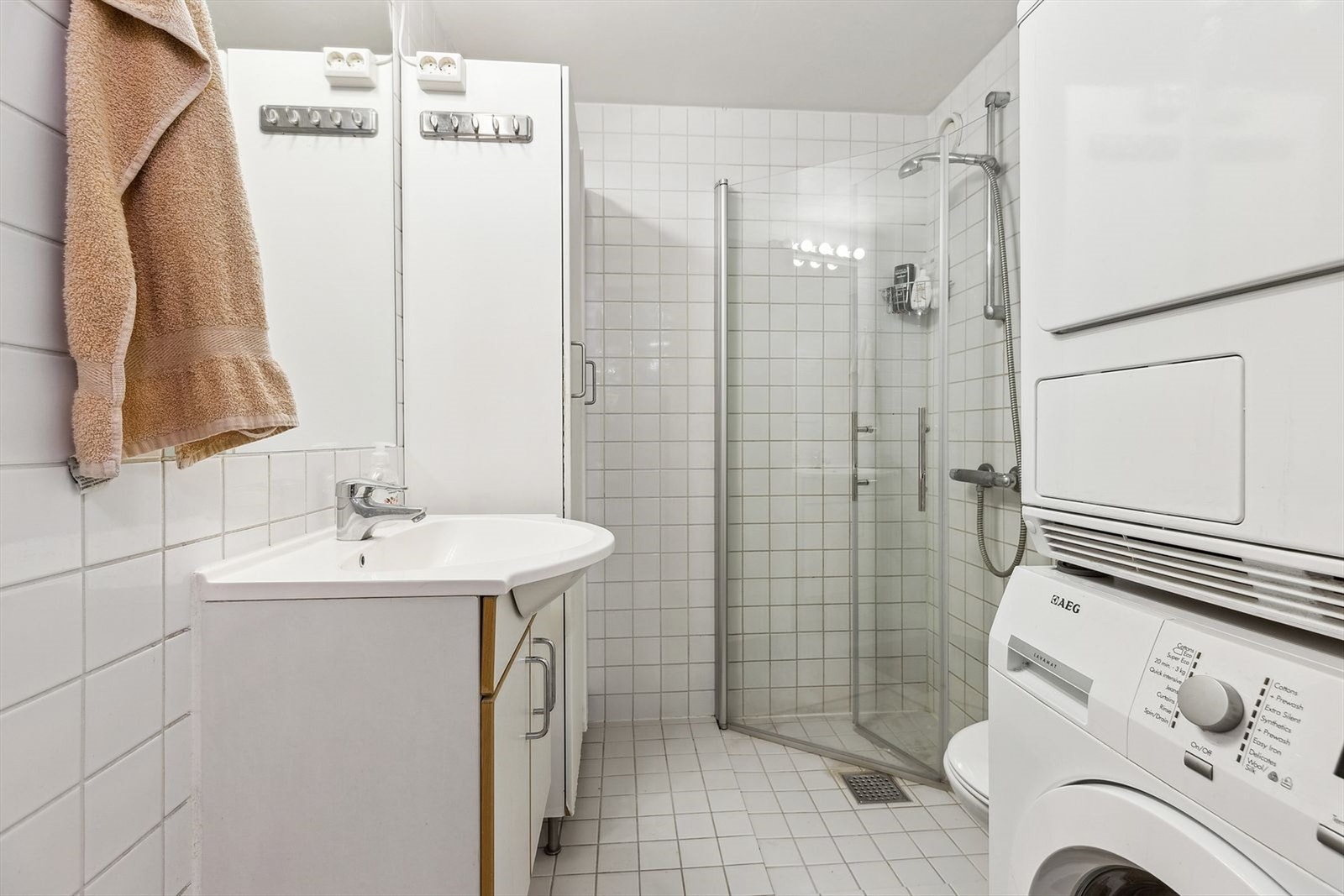 Flislagt bad utstyrt med gulvvarme, servant med underskap og speil, dusjhjørne og wc. Vaskemaskin medfølger. Galleribilde