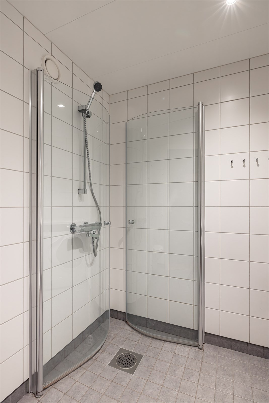 Det er innredet med benkeskap med glatte fronte, dusj med dører i herdet glass, veggfestet klosett og servant i helstøpt plate. Galleribilde