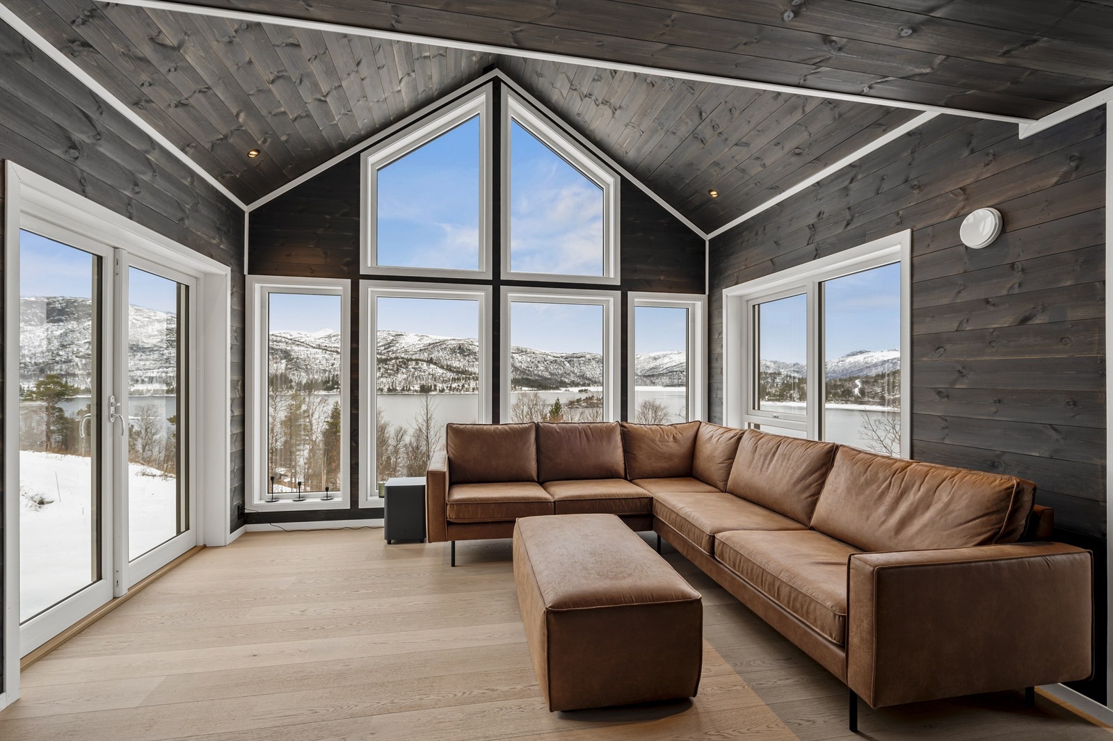 Moderne og koselig hytte med panel på vegger og tak og åpen himling i stuen Galleribilde