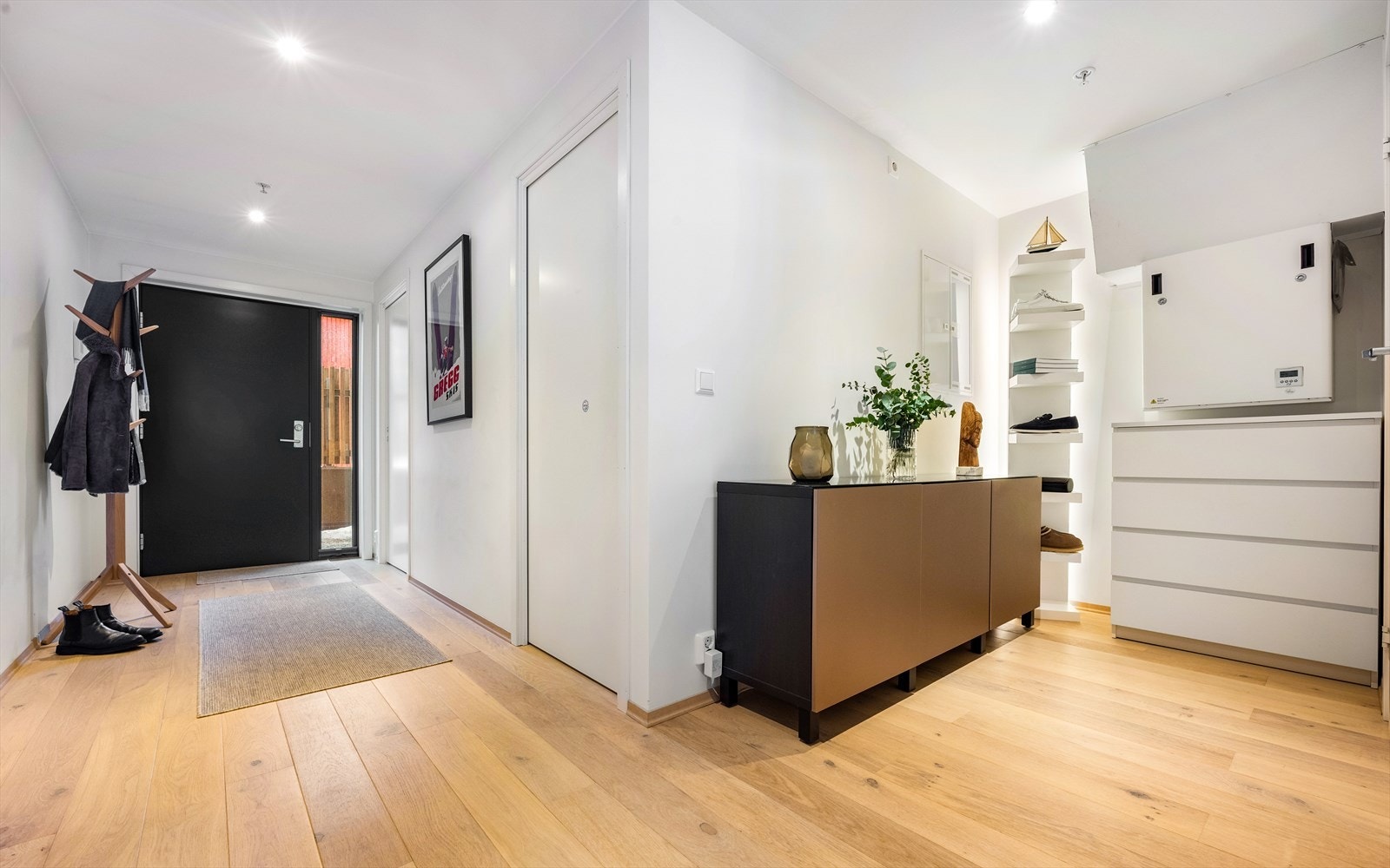 Lys entré med downlights, og videre inn til gangen med skap og stilige løsninger for å oppbevaring av klær og sko. Galleribilde