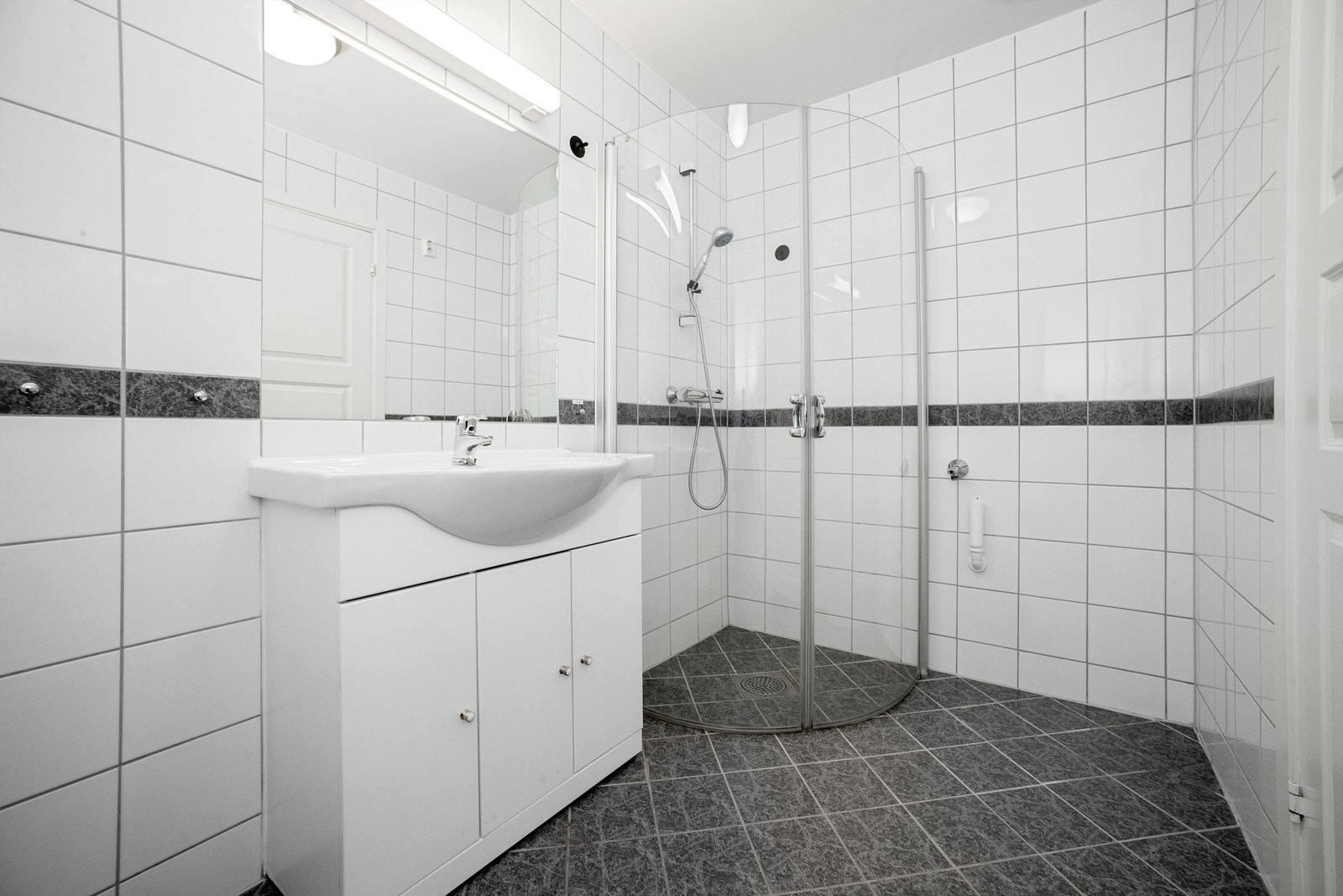 Dusjhjørne med innfellbare dører av glass samt opplegg for vaskemaskin og tørketrommel. Galleribilde