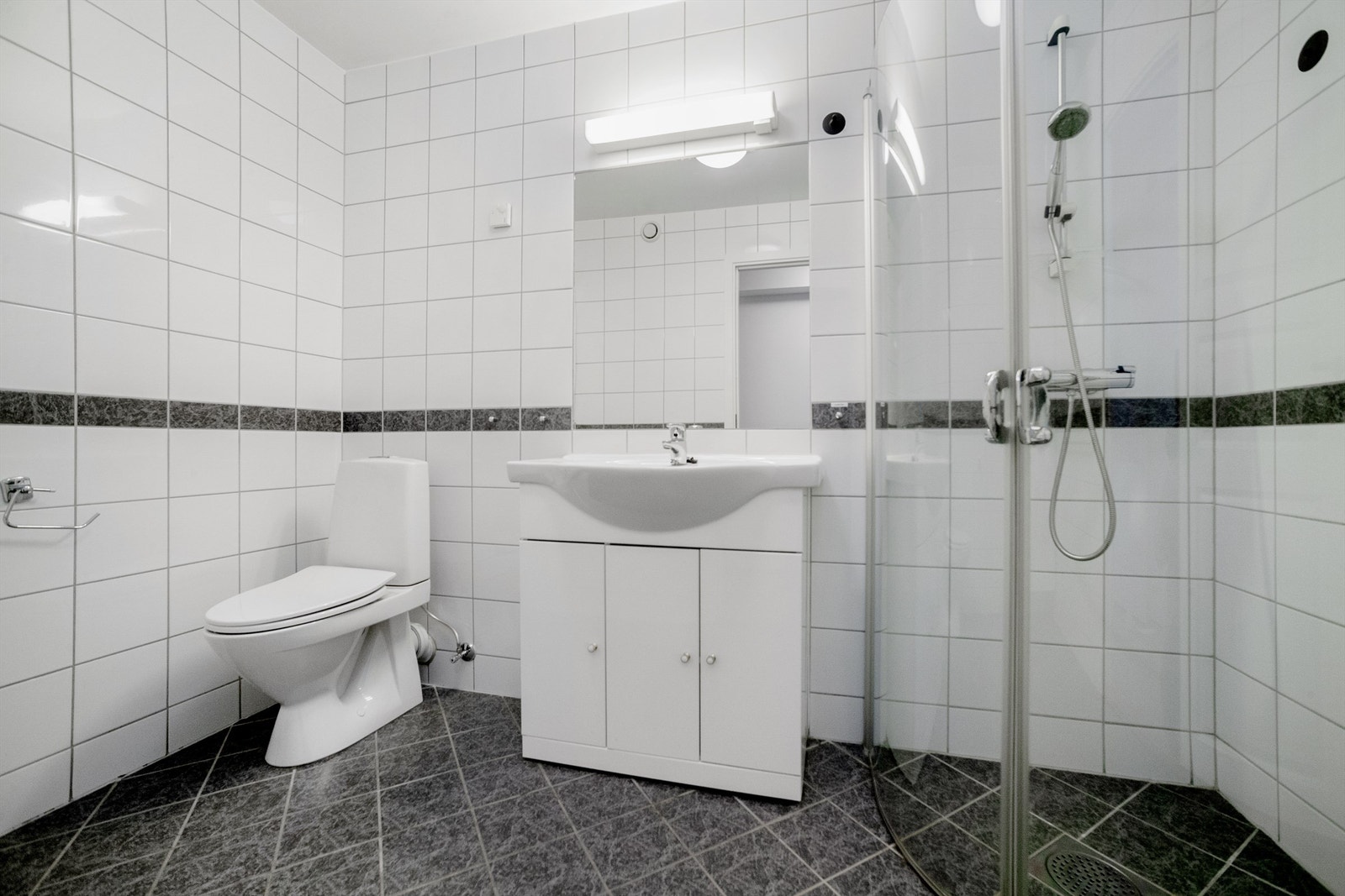 Vannbåren varme og servantinnredning med slette, lyse fronter og heldekkende servant med ett-greps armatur. Galleribilde