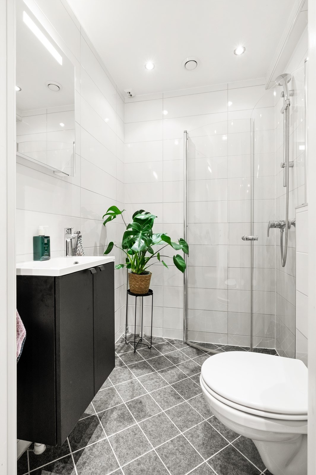 Det er montert downlights i himlingen og gulvvarme for en lun og behagelig start på dagen. Innredningen består av servant på innredning, vegghengt toalett og dusjhjørne med svingbare glassdører. Galleribilde