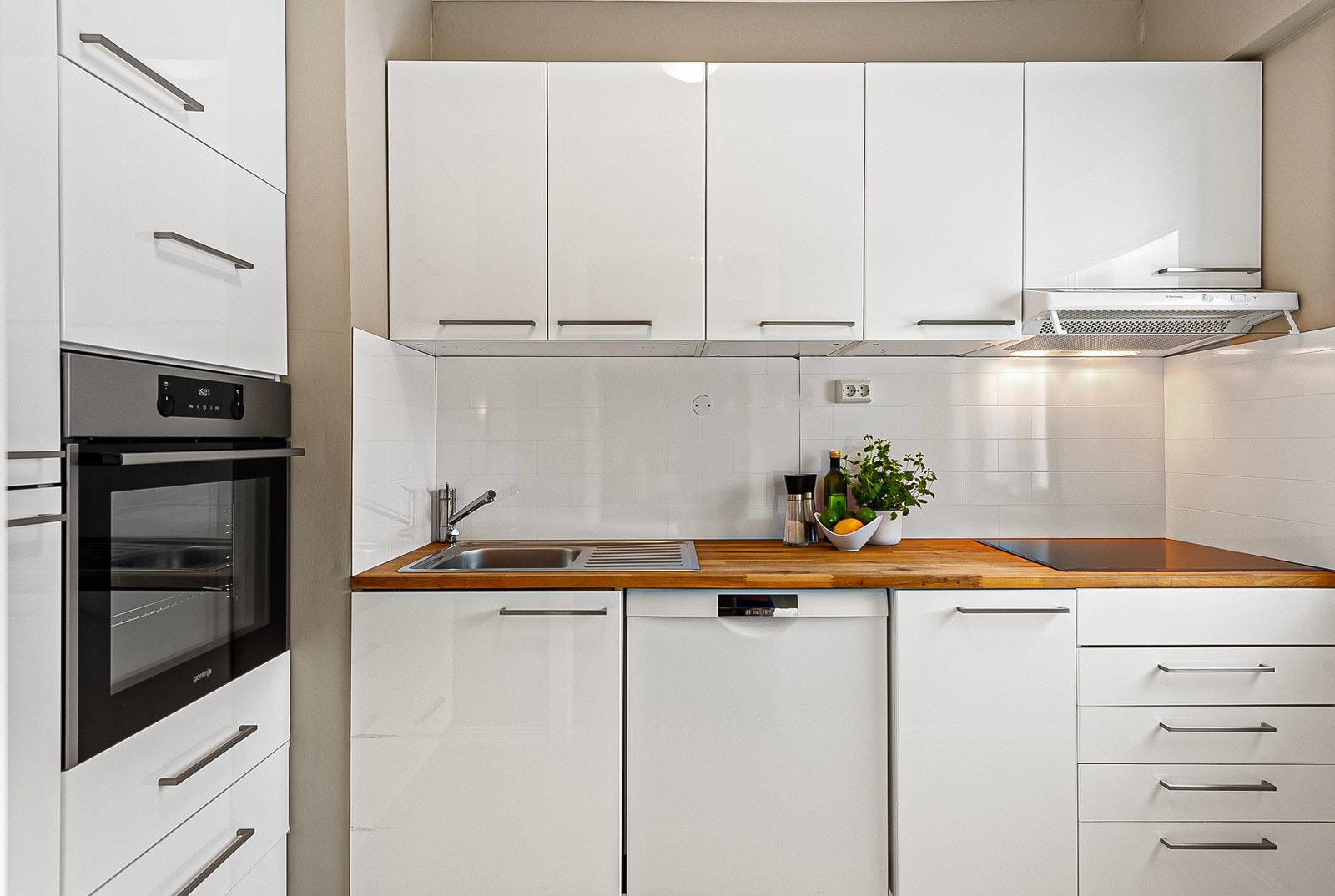 Lyst, delikat kjøkken med slette fronter og benkeplate i tre Galleribilde