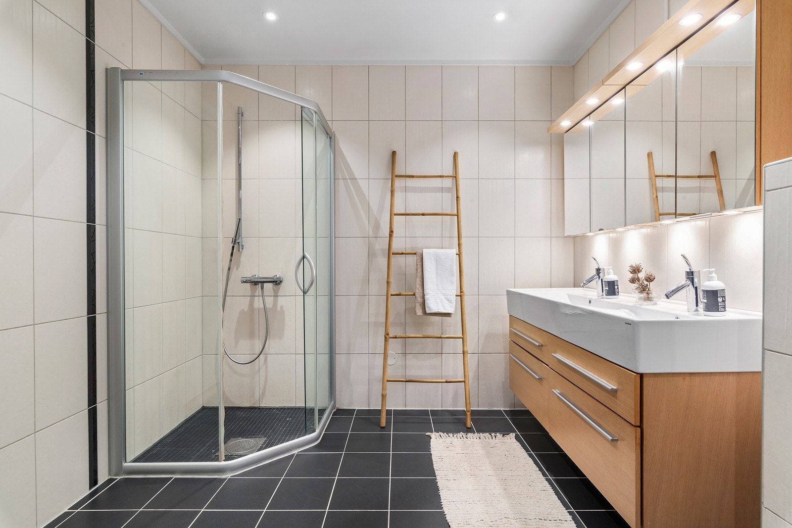 Bad i andre etasje med fliser på gulv og vegger. Her er dusjhjørne, vegghent toalett, innredning med servant og opplegg for vaskemaskin og tørketrommel. Galleribilde