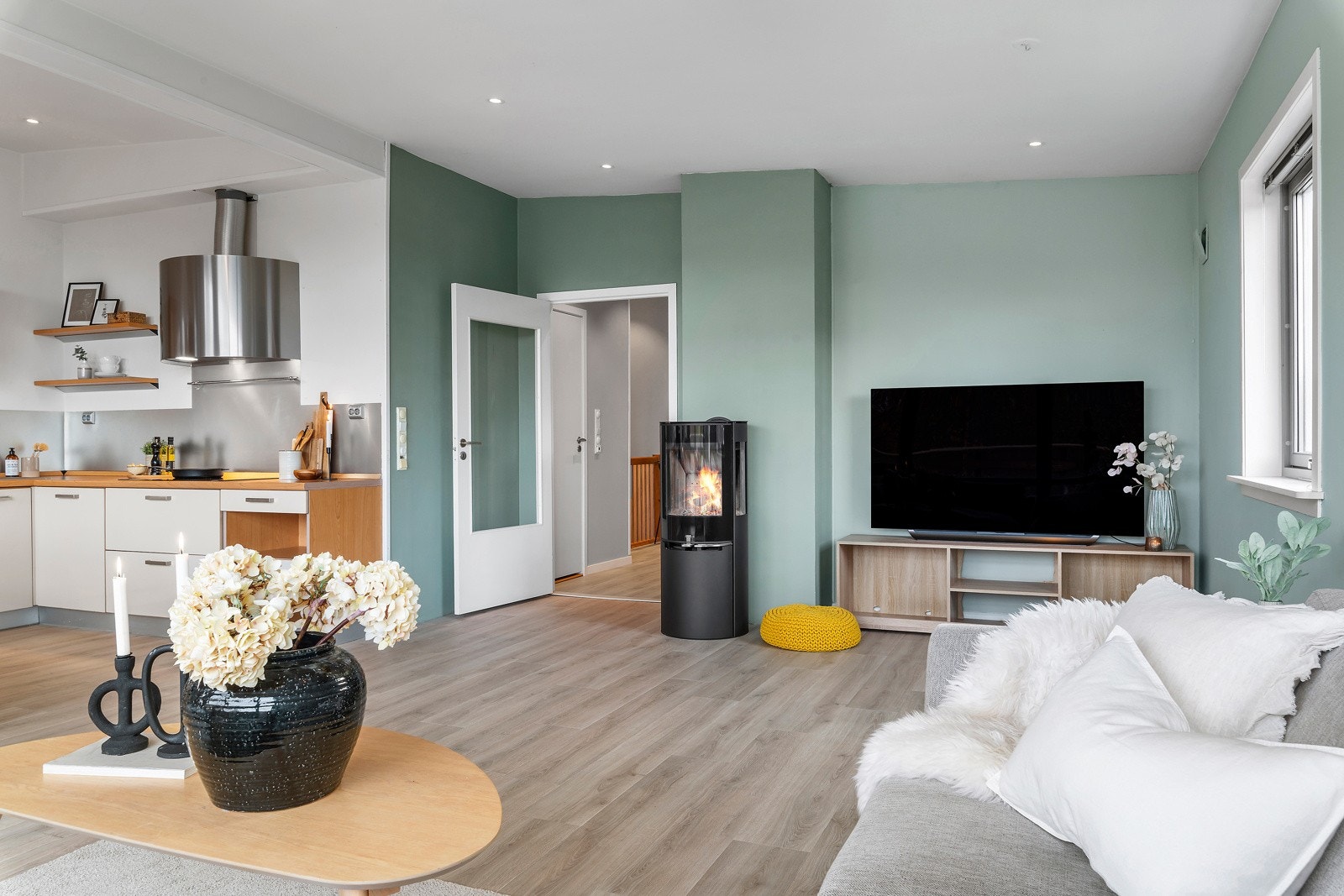 Det er enstavs laminat på gulvet og malte tak- og veggflater. Peisovn med glassdør. Galleribilde