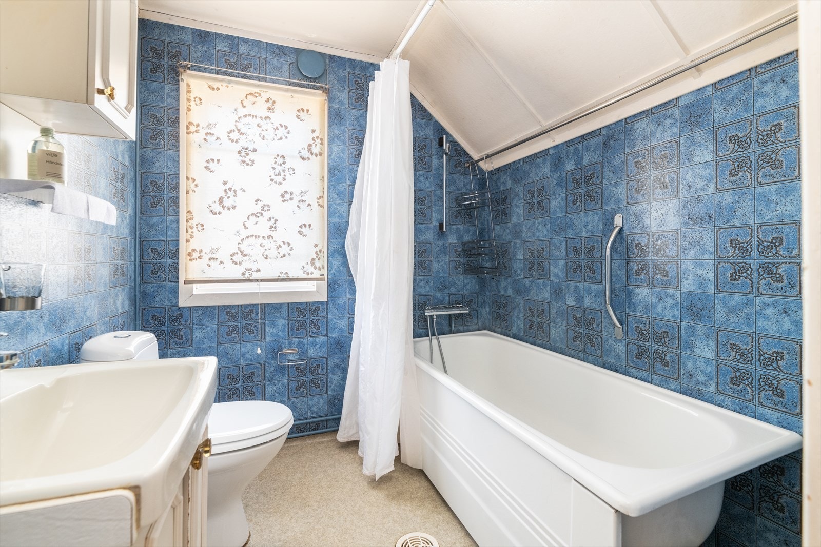 Eldre bad med belegg på gulv, våtromstapet på vegger og malte plater i tak. Galleribilde