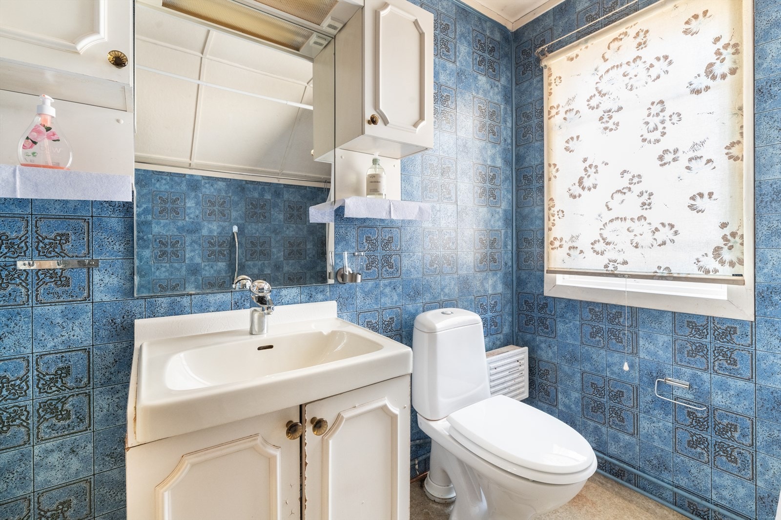 Badet er innredet med toalett, badekar med vegghengt dusj og servantmøbel med underskap, vegghengt skap og speil. Det er panelovn på vegg. Galleribilde