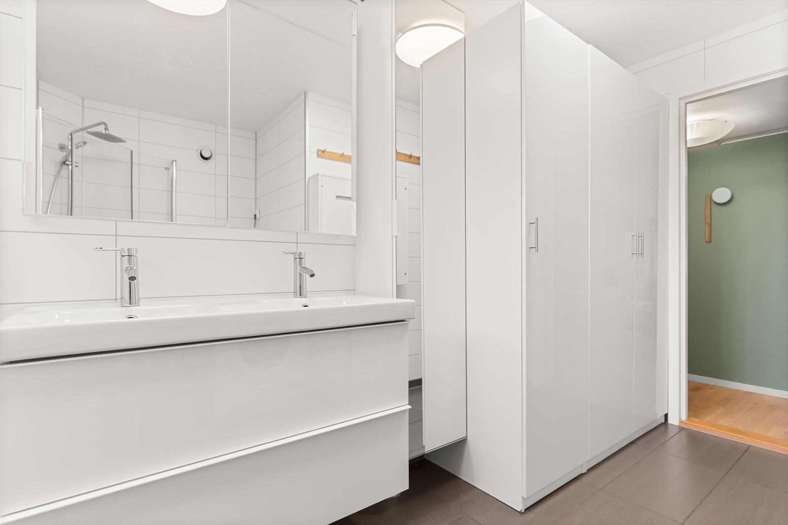 Flislagt og tidløst bad med varmekabler i gulv, og garderobeskap som gir gode oppbevaringsmuligheter Galleribilde