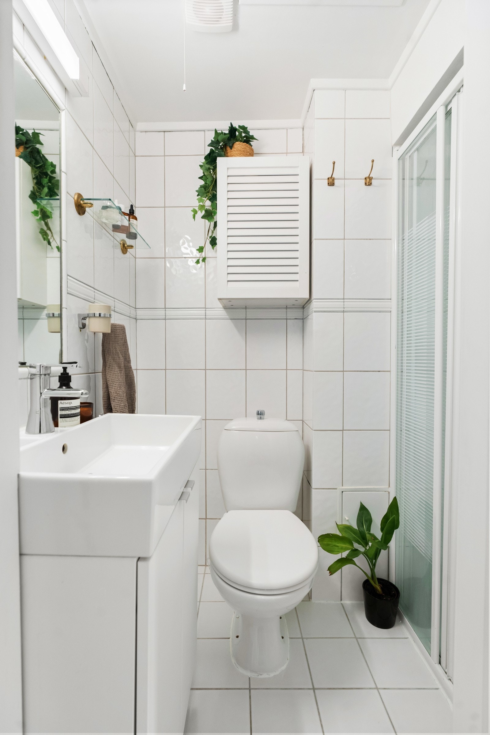 Baderom med gulvstående toalett, dusjhjørne samt servantskap med slette fronter. Galleribilde