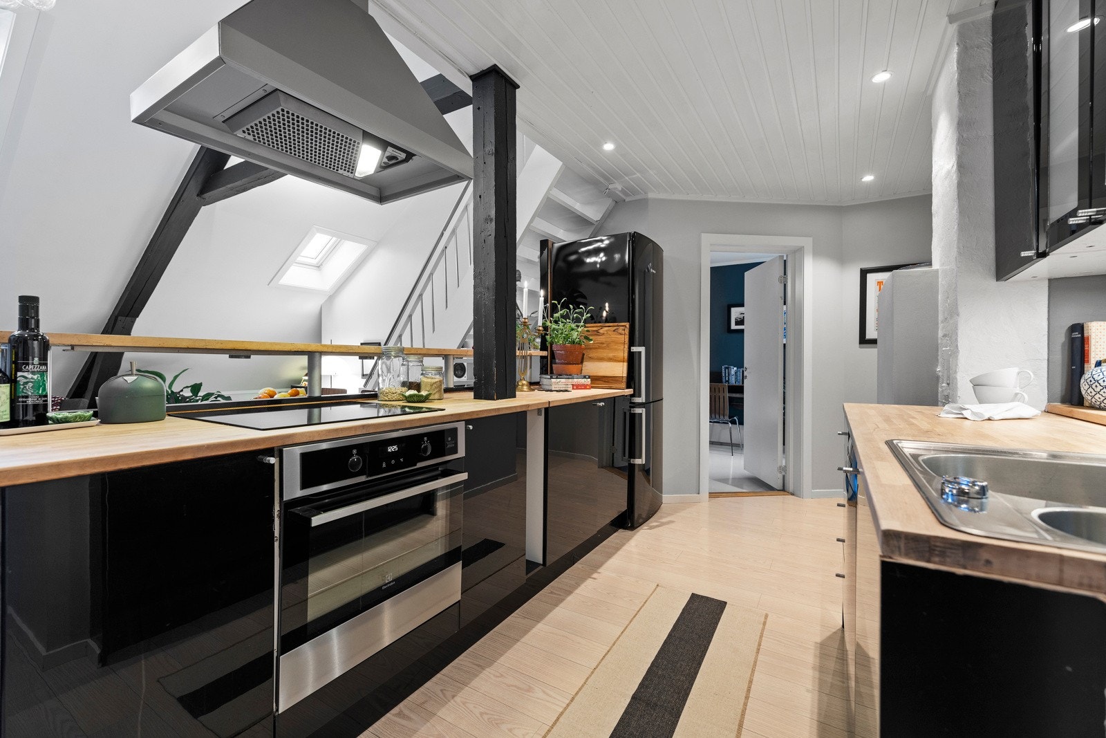 Innredning med glatte, folierte fronter og benkeplate i heltre. God skap- og benkplass samt arbeidsflater til matlaging. Galleribilde