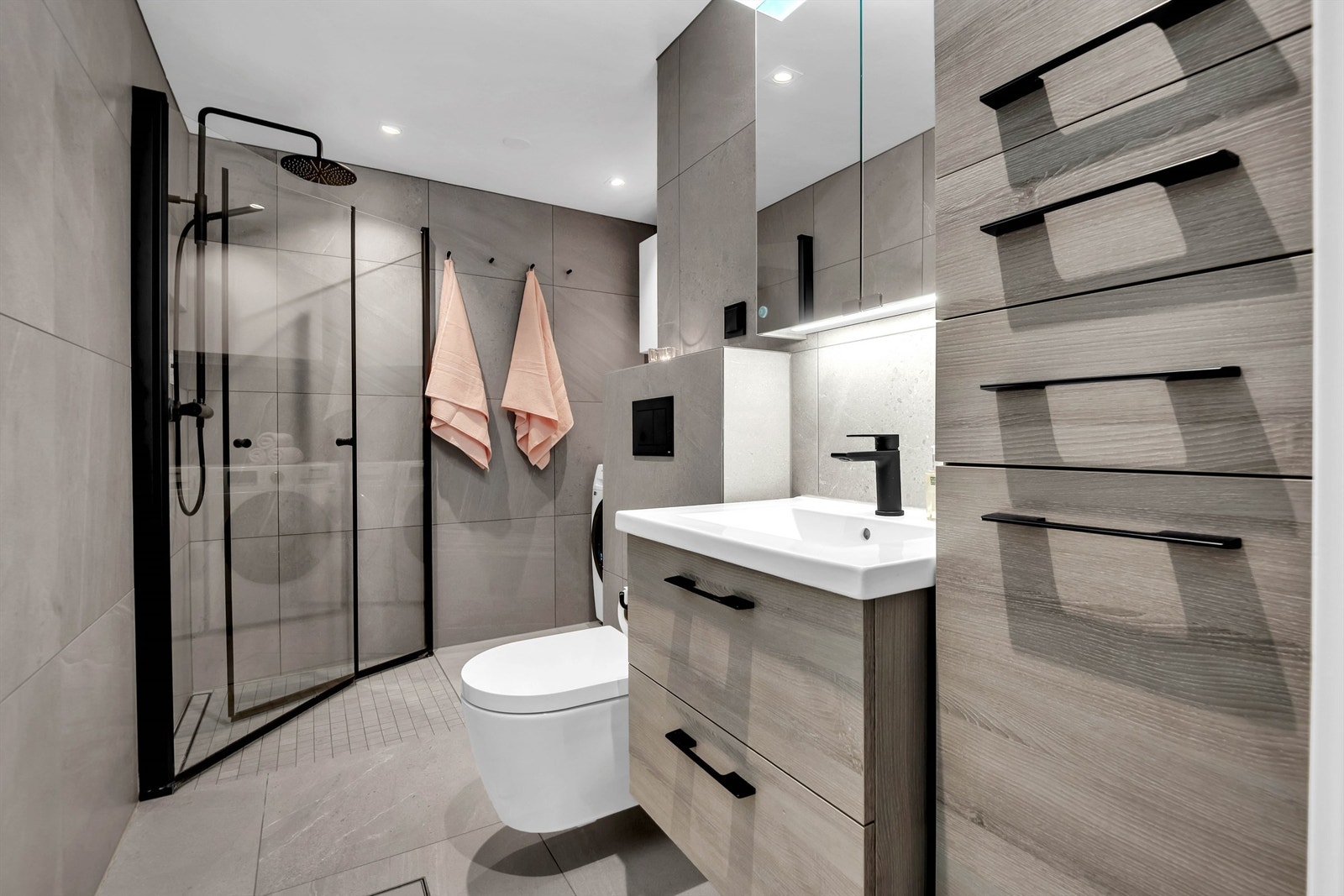 Baderomsinnredning består av flislagte vegger og malt slett himling med downlights. Skuffer, servantskap med 1-greps blandebatteri, speilskap over servant, avløpsrør av plast og vannrør i rør-i-rør. Galleribilde