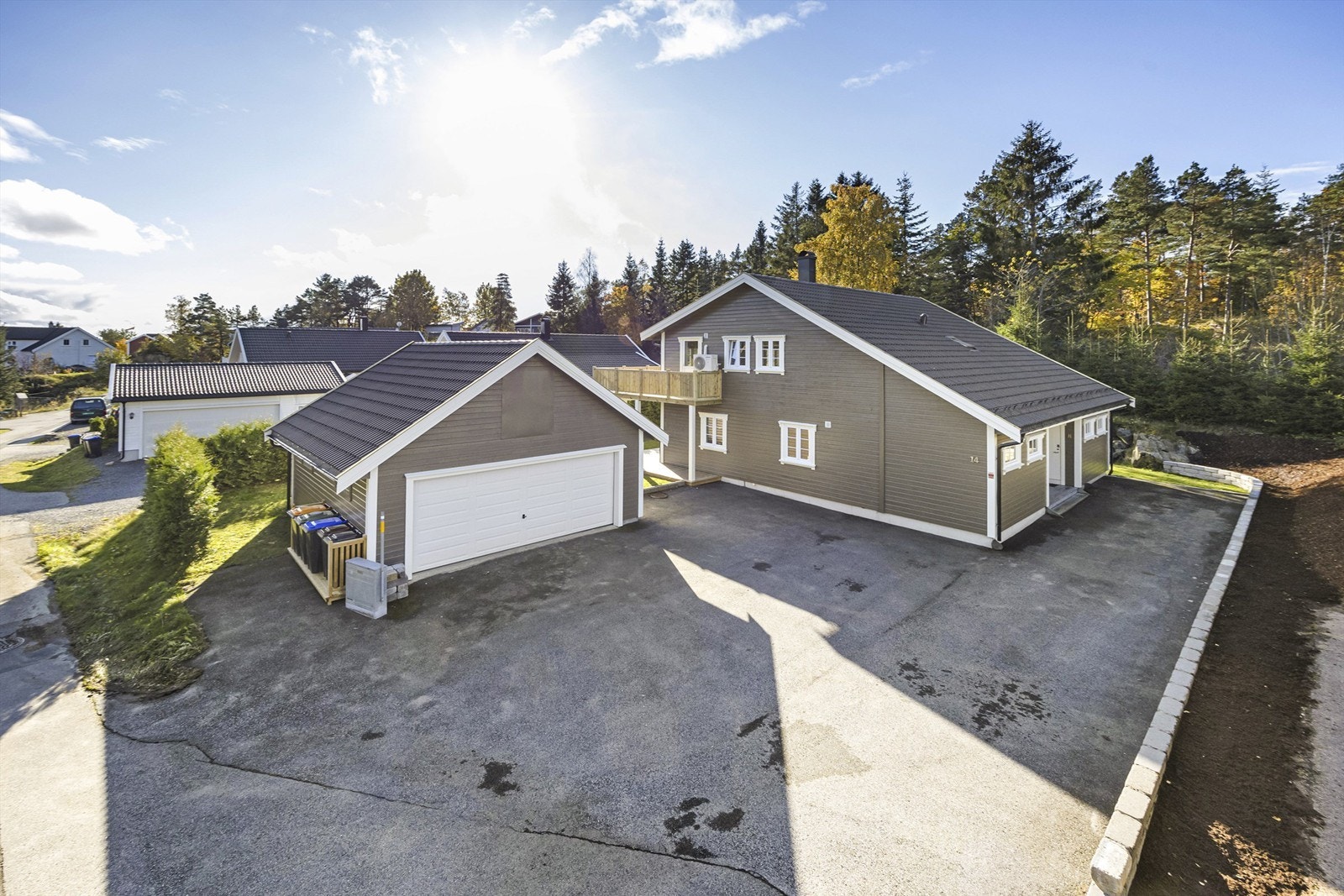 Stort asfaltert tun med dobbel garasje, mur, plen og beplantning Galleribilde