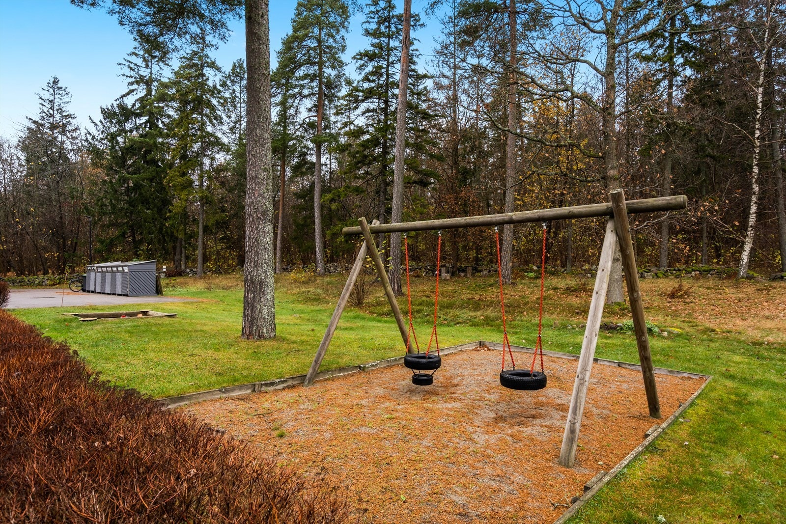 Tomten ligger inntil et skogholt som i kombinasjon med nærhet til vannet gir et idyllisk inntrykk. Her er bla. a. huskestativ og sandkasse for de små. Galleribilde