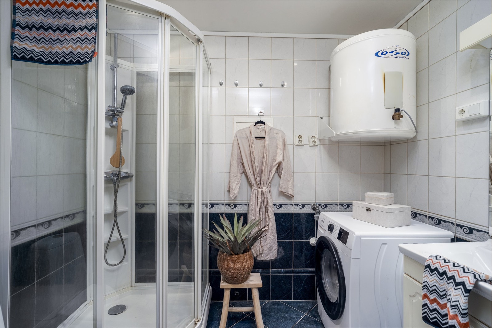 Helfliset baderom med varmekabler på gulv. Innredet med dusjkabinett, baderomsservant, opplegg til vaskemaskin og toalett. Galleribilde