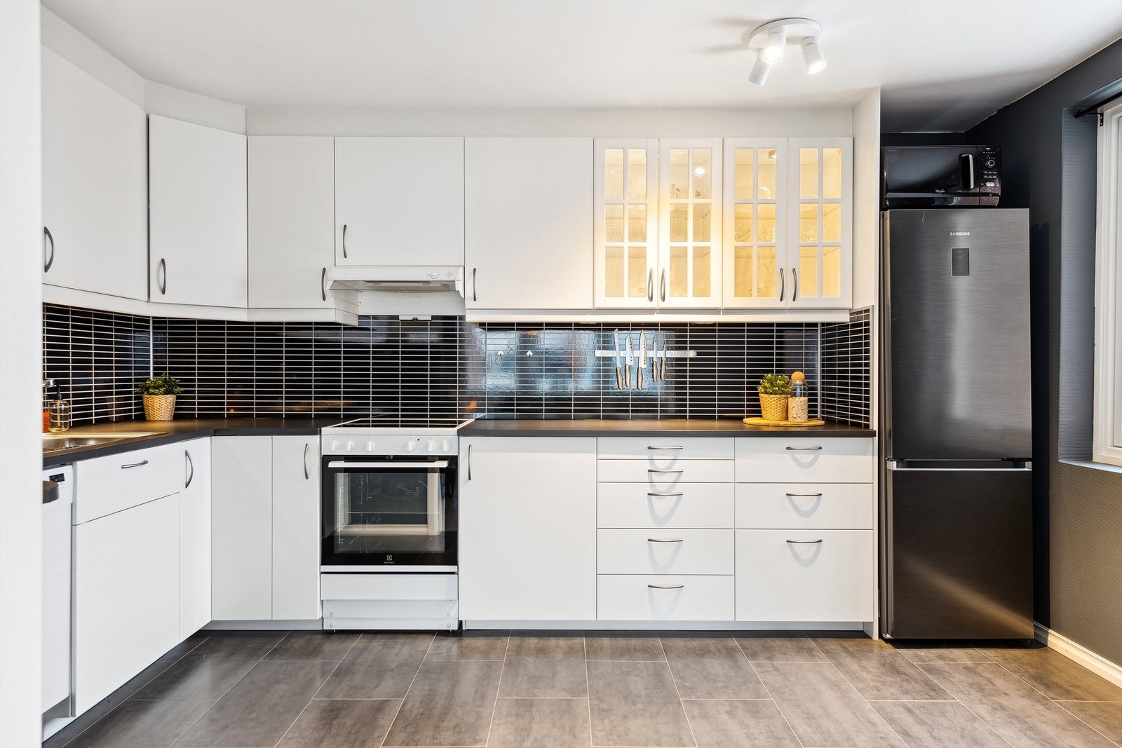 Lyst kjøkken med plass til frittstående komfyr, oppvaskmaskin og kjøl-/fryseskap. Galleribilde