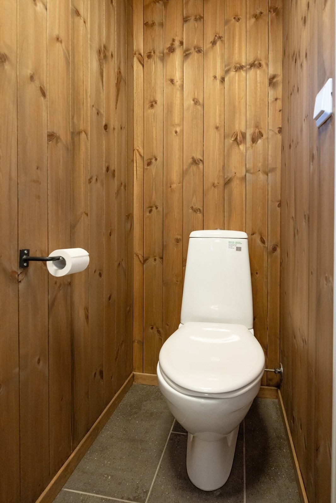 Toalettrom med flislagt gulv, panel på vegger og i himling. Galleribilde