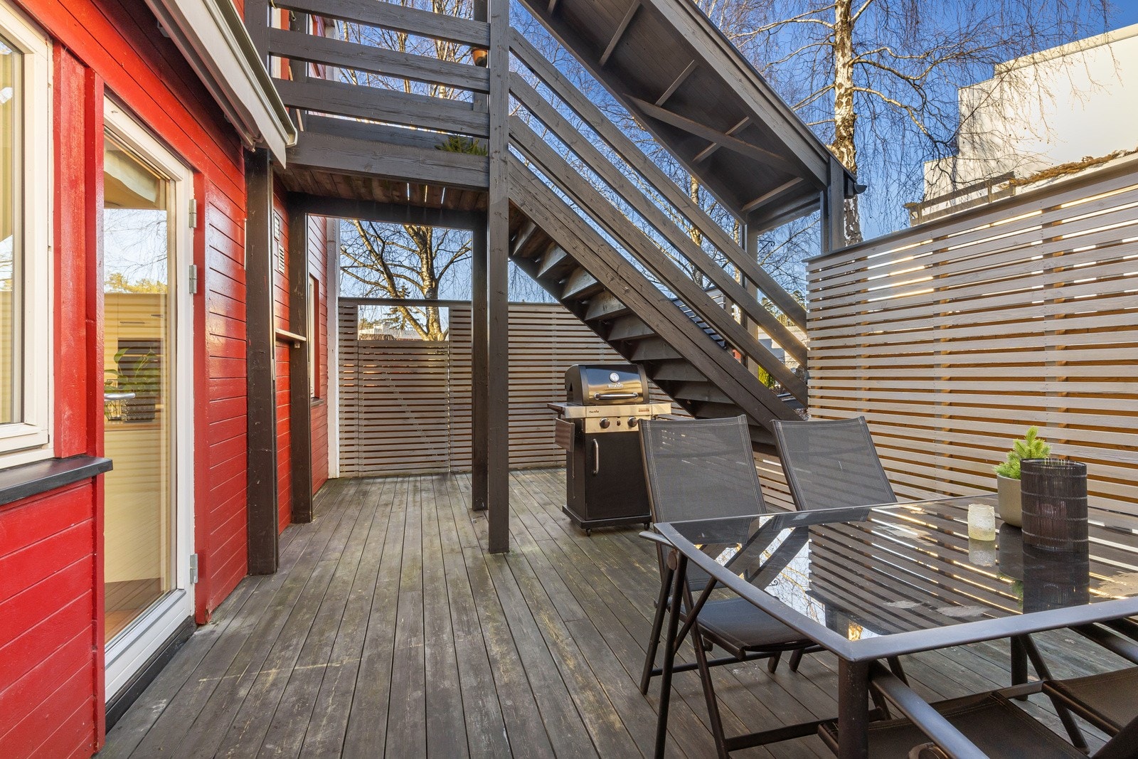 Terrassen måler ca. 28 kvm, og rammes fint inn av store levegger med spiler. Praktisk port i leveggen fører ut til fellesarealet. Galleribilde