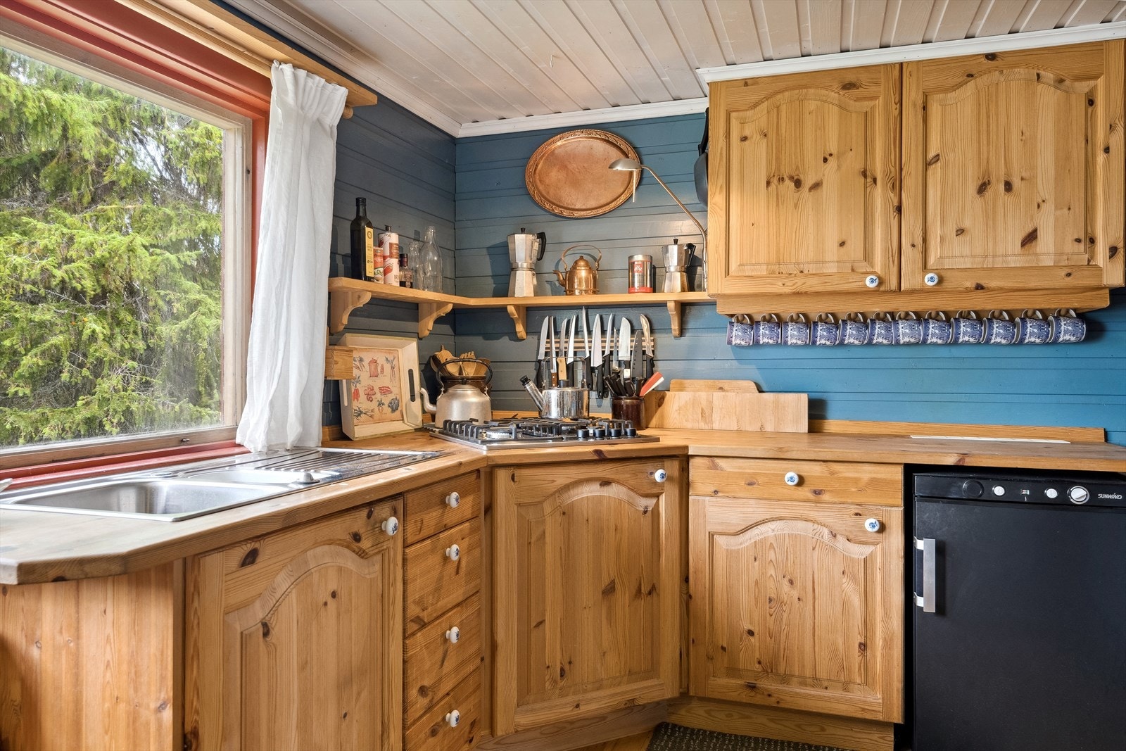 Kjøkkeninnredning i heltre med over- og underskap. Benkeplaten er i heltre og oppvaskkum av stål. Galleribilde