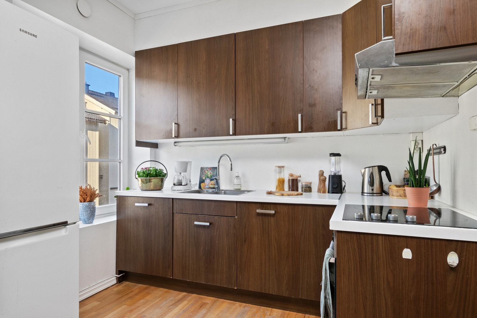 Kjøkkenet er designet i en hendig L-form og har godt med skap- og benkeplass Galleribilde